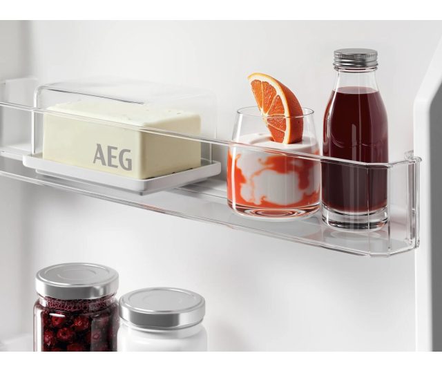 Deurvak met AEG boter-bakje, glas met sinaasappel en fles rode vruchtendrank