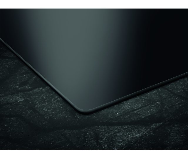 AEG TT64CB00CB inductie kookplaat met afzuiging detailshot van afgeronde rechteronderhoek van het zwarte glaskeramische oppervlak
