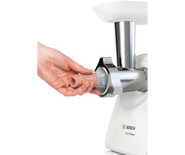 Hand voedt ruw vlees in Bosch MFW2520W vleesmolen invoertrechter