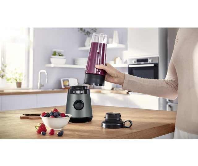 Bosch MMB2111S in gebruik op keukentafel met paarse smoothie in mengbeker en losse bessen