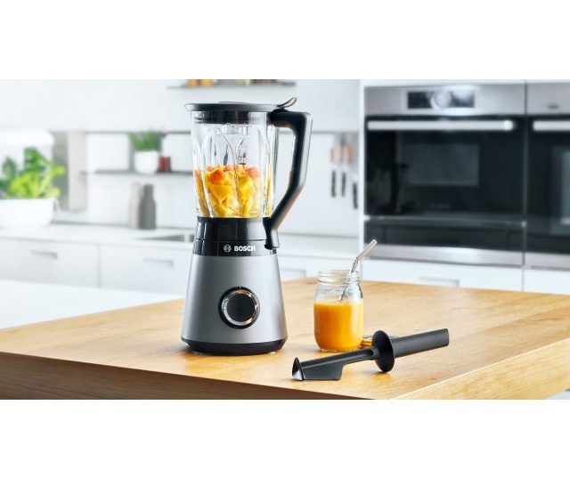 Bosch MMB6172S blender in moderne keuken op houten werkblad, kan met geel vruchtensap en mengstaaf ernaast