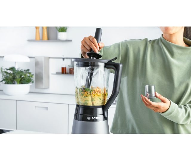 Bosch MMB6172S blender in gebruik met groen-grove ingrediënten in kan, staafmixer ernaast op keuken