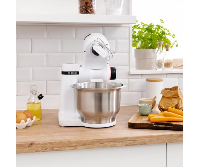 Bosch MUMS2EW00 keukenmachine frontaanzicht op werkblad met garde in mengkom