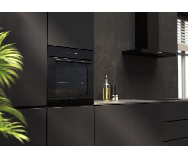 ETNA MO516GLS geïnstalleerd in zwarte keuken met keramische achterwand