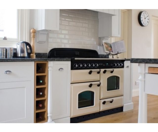 De FALCON Classic 110 gas/elektro afgebeeld in de kleur creme en geplaatst in een bijpassende keuken