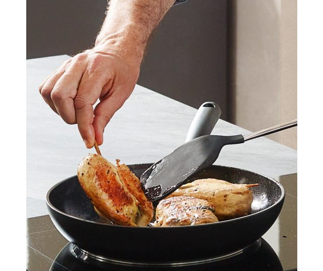 Fissler Essential koekenpan in gebruik op kookplaat met vlees en metalen spatel
