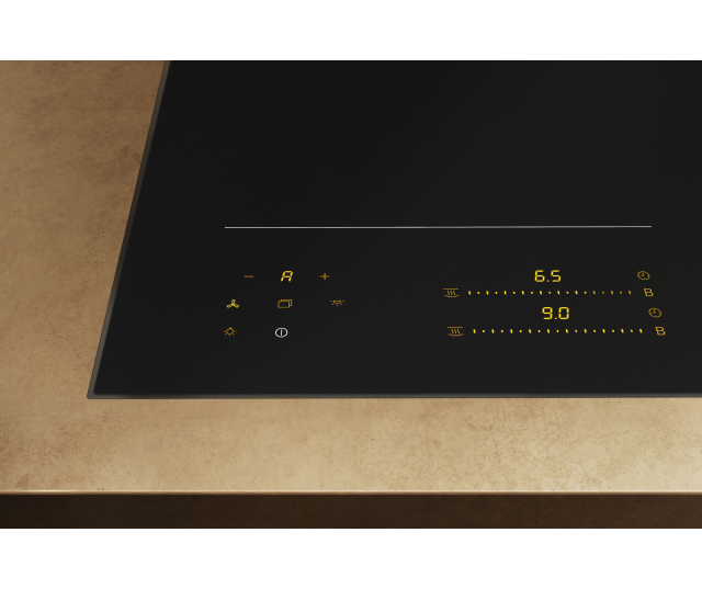 Miele KM 8565 FL inductiekookplaat in keukenblad geplaatst, schuine zijaanzicht met bedieningselementen en gele LED-indicatoren zichtbaar