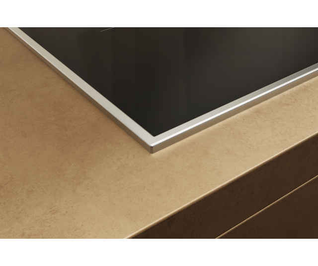 Miele KM 8482 FR inductiekookplaat inbouwdetail met chromen rand en aansluitkant op houten werkvlak