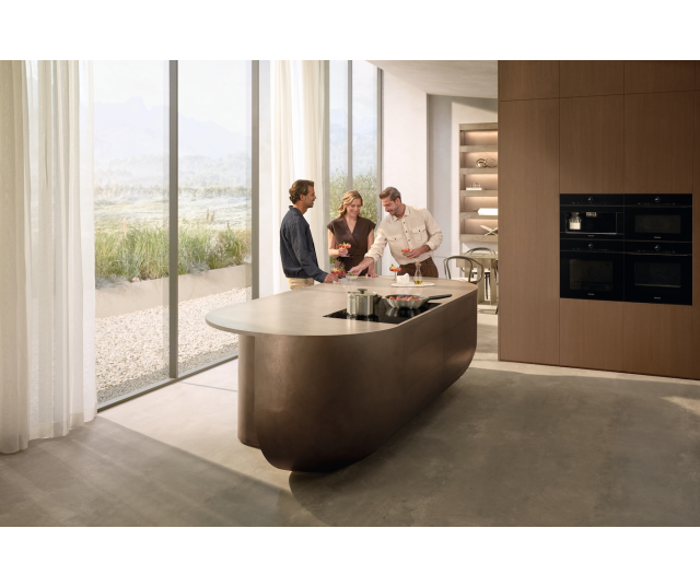 Miele KM 8895 FL inductiekookplaat in moderne keuken met eiland en personen