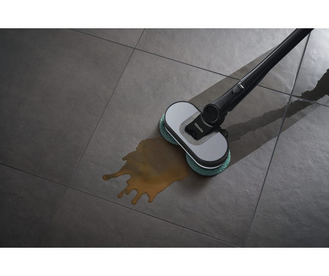 Miele TriflexHX3Aqua hybrid zuigmotor reinigt natte vloeistof op tegelvloer met groene doek
