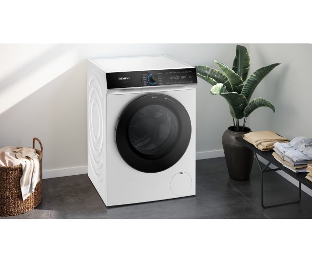 Siemens WG66B2ABNL wasmachine in woonruimte met gesloten deur en kant profiel