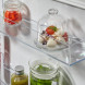 Geopend bovenste koelgedeelte van AEG TC7NS181ES met glas containers, kruideniersartikelen en frisse producten op transparante schappen