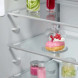 Detail middelste schap met glazen bak met dessert en gekleurde flesjes