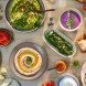 Bosch MSM66110 staafmixer tussen diverse gerechten en ingrediënten op houten werkblad