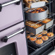 Falcon Classic Deluxe 2026 110 Inductie fornuis, geopende bovenoven met meerlagige bakplaten en gebakken deegwaren
