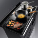 Geopend kookoppervlak van Falcon Estel Deluxe 110 met wok, steelpannen en vlees op grillplaat