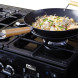 Gasfornuis met wok op gaspit, noodles en groente worden bereid op het kookblad