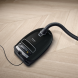 Miele Complete C3 Select Parquet op houten vloer met slang aangesloten, zijaanzicht