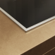 Miele KM 8482 FR inductiekookplaat inbouwdetail met chromen rand en aansluitkant op houten werkvlak