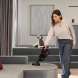 Miele TriflexHX3Cat&Dog in gebruik in woonkamer, vrouw zuigt bank schoon naast hond